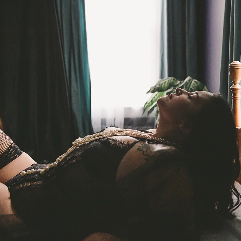 woman in black feather robe in repose on bed